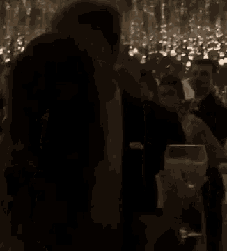 a man and a woman are kissing while holding glasses of champagne in a dark room .