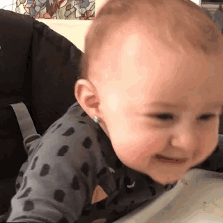 a baby is sitting in a high chair and smiling at the camera .