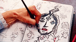 a person is drawing a picture of a woman 's face in a notebook .