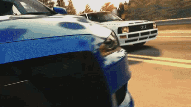 two cars are driving down a road and one has the word audi on the front