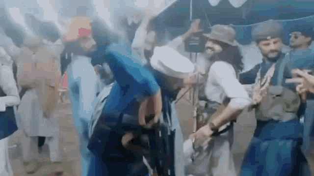 a group of men are dancing in front of a tent while holding guns .
