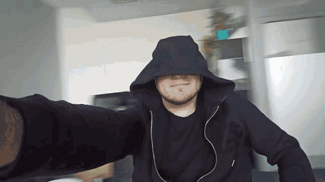 a man in a black hoodie is taking a picture of himself