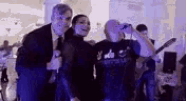 a group of people are standing next to each other in a room with a microphone .