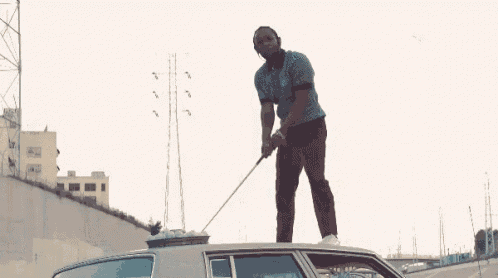 a man is standing on top of a car in a parking lot near a bridge