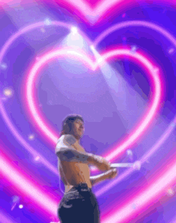 a shirtless man is standing in front of a heart shaped neon sign .