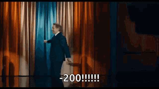 a man in a suit and tie is standing on a stage with his arms outstretched and saying -200 !!!