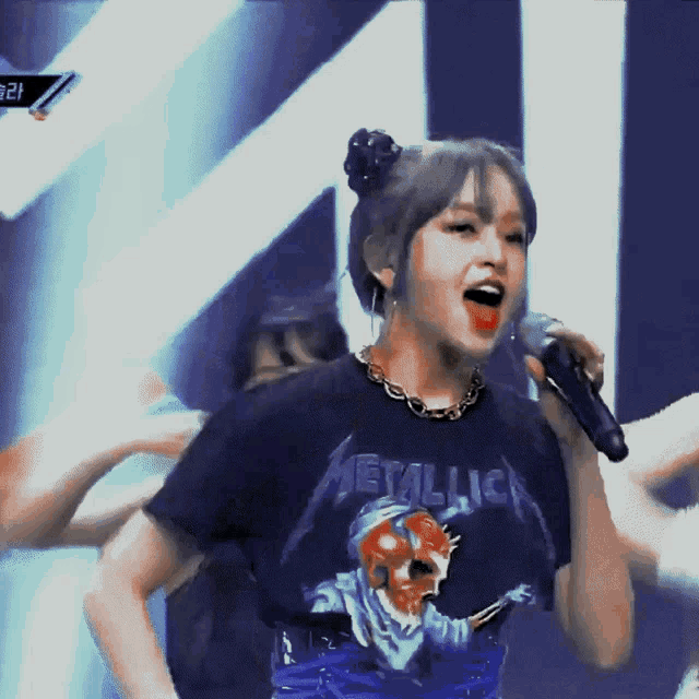 a girl singing into a microphone wearing a black metallica shirt