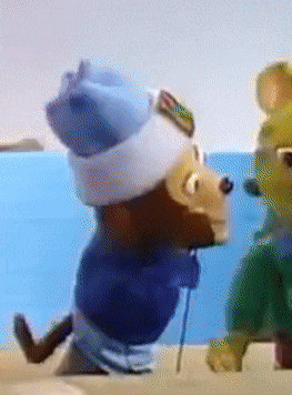 a teddy bear wearing a blue hat and goggles is walking on the beach