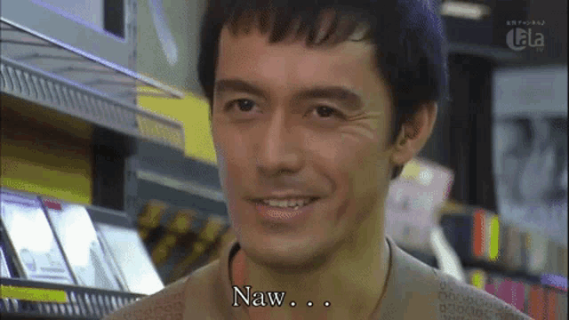 a man is smiling in front of a shelf that says naw