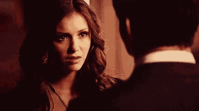 a woman in a black dress is looking at a man in a black suit .