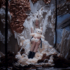 a woman sits on a pile of stuffed animals holding a teddy bear