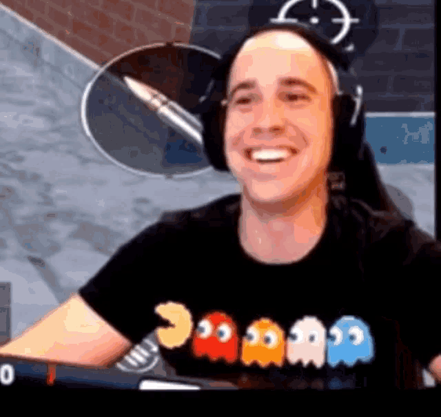 a man wearing headphones and a pacman t-shirt is smiling .