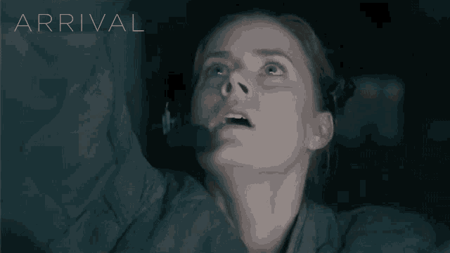 a woman wearing a headset looks up at the word arrival above her