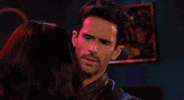 a man and woman are looking at each other in front of a painting