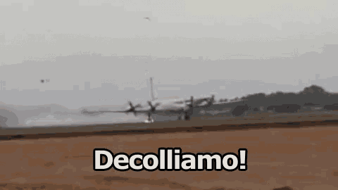 a plane is taking off from an airport runway and the words decolliamo are visible in the foreground