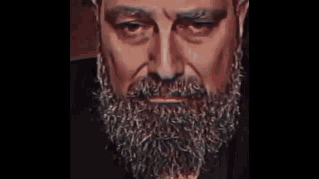 a close up of a man 's face with a beard and mustache smoking a cigarette .