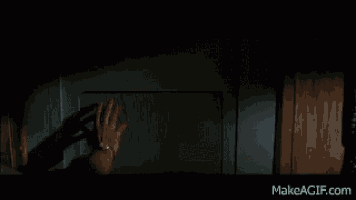 a man is holding a woman in his arms in a dark room in a movie .