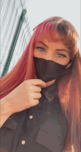 a woman with long red hair wearing a black mask