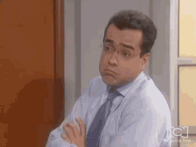a man in a suit and tie is making a funny face with his hands folded .