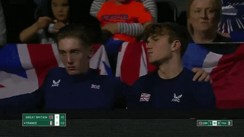 two young men are sitting next to each other in a stadium watching a game .