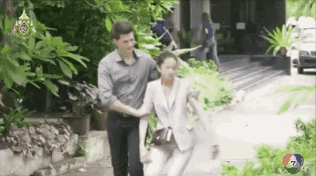 a man is holding a woman 's hand as she runs down a street .