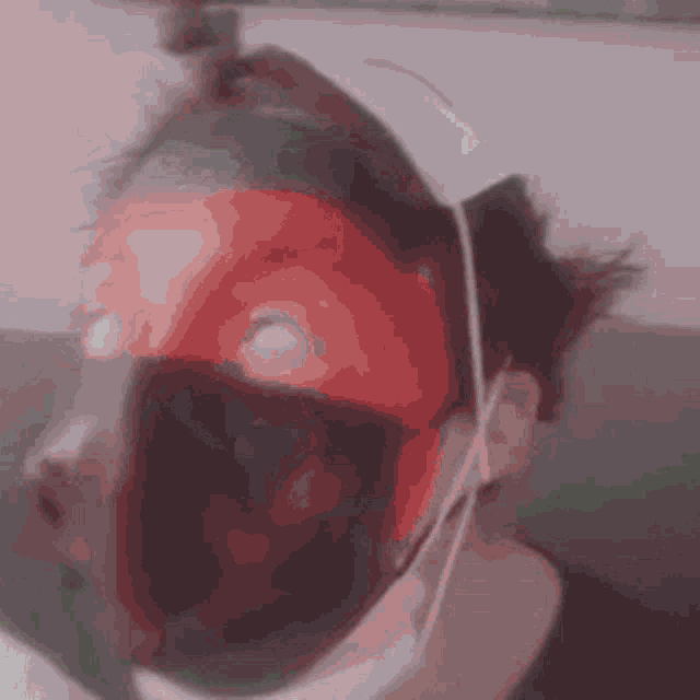 a person wearing a mask with a red stripe on their face .