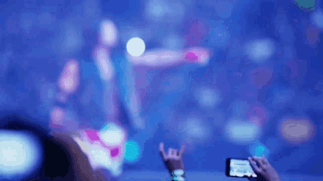 a blurry picture of a person taking a picture of a concert with their phone .