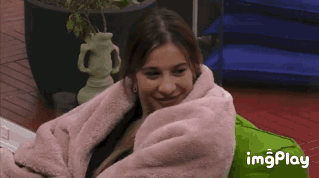 a woman is wrapped in a pink blanket and smiling