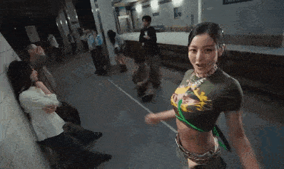 a woman in a crop top is standing in a hallway with people .