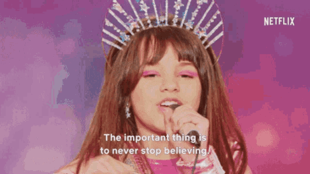a little girl singing into a microphone with the words the important thing is to never stop believing