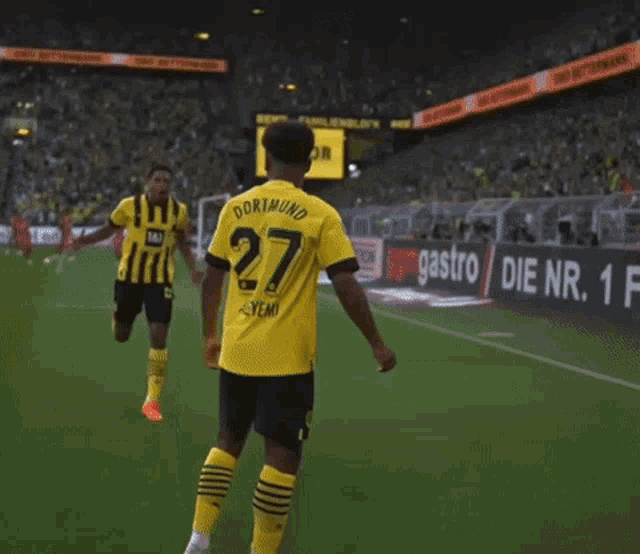 a soccer player wearing a yellow and black jersey with the number 27 on it