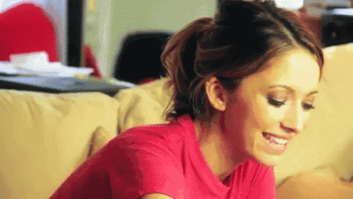 a woman in a pink shirt is sitting on a couch smiling