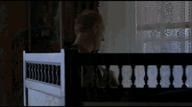 a man in a red shirt is looking out a window behind a railing