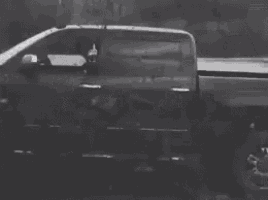 a black and white photo of a truck driving through a muddy area .