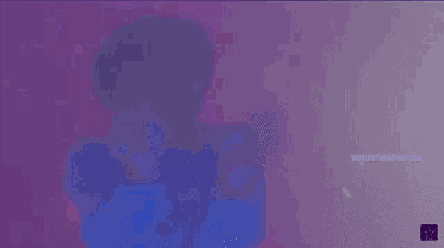 a person is standing in a dark room with a purple background and a purple light behind them .