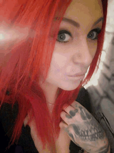 a woman with red hair has a tattoo of a skull on her arm