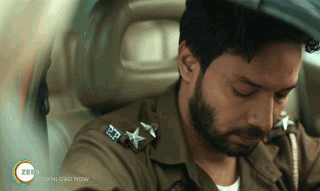a man with a beard is sitting in the back seat of a car with the words zee download now on the bottom right