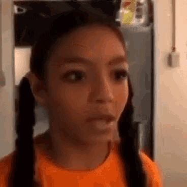 a young girl with pigtails is making a funny face .