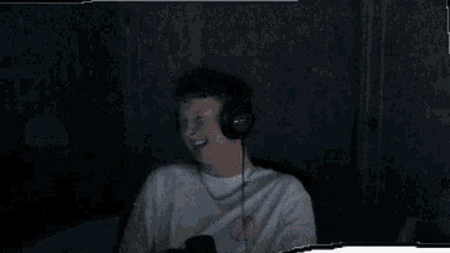 a young man is wearing headphones and smiling in front of a microphone .