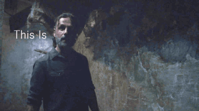a man with a beard is standing in front of a wall that says where u
