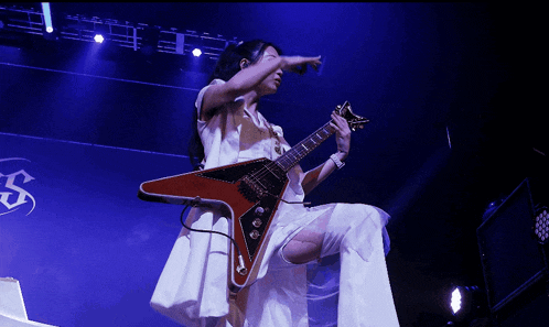 a woman in a white dress is playing a red guitar on stage