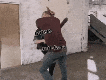 two men are fighting in a room with haters and anti-fans written on them
