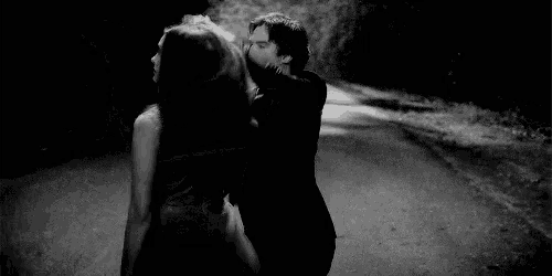 a man is holding a woman 's hair while dancing on a road .