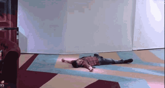 a man in a plaid shirt is laying on the floor with his arms outstretched