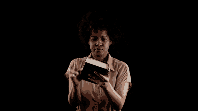 a woman is holding a bible in her hand and pointing at it