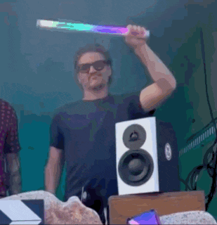 a man is holding a light up stick in front of a speaker with the letter o on it