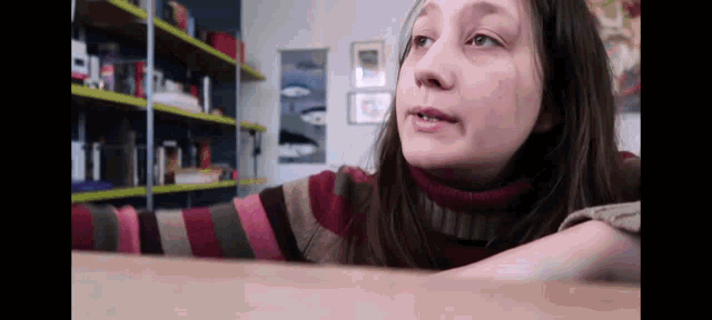 a woman wearing a striped sweater is sitting at a table