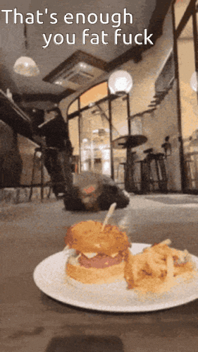 a hamburger and french fries on a white plate with the words that 's enough you fat fuck