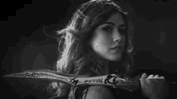 a black and white photo of a woman holding a large sword .