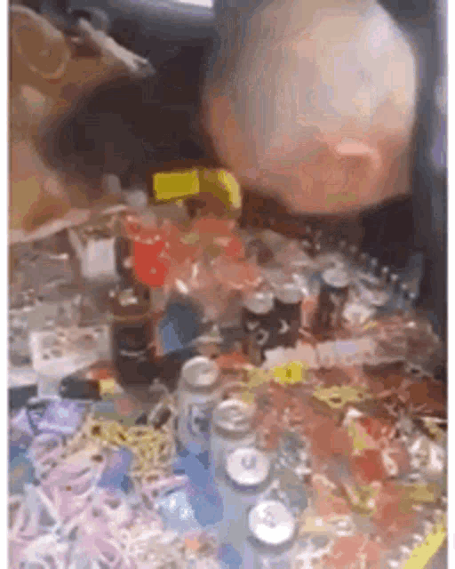a bald man is sitting in a car surrounded by bottles and cans of beer .